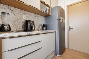 Eine Küche mit einer Granit Arbeitsplatte, einer Kaffeemaschine, einem Mixer und einem Edelstahl-Kühlschrank.