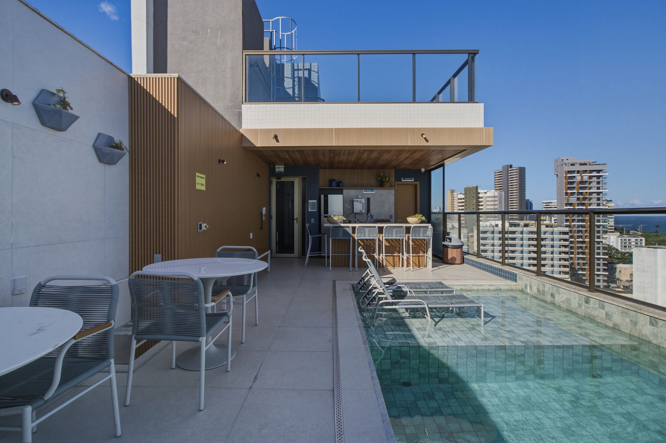 Una terraza en la azotea con piscina, mobiliario exterior y vistas del horizonte urbano.