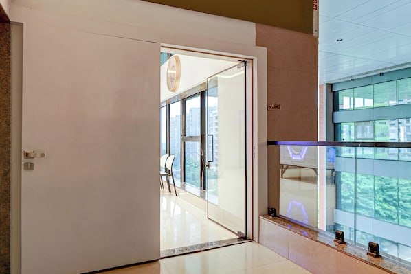 A modern interior with a glass door leading to a balcony with a city view. - Collection O Airport Rd Frmly Nano Pod (Surat)