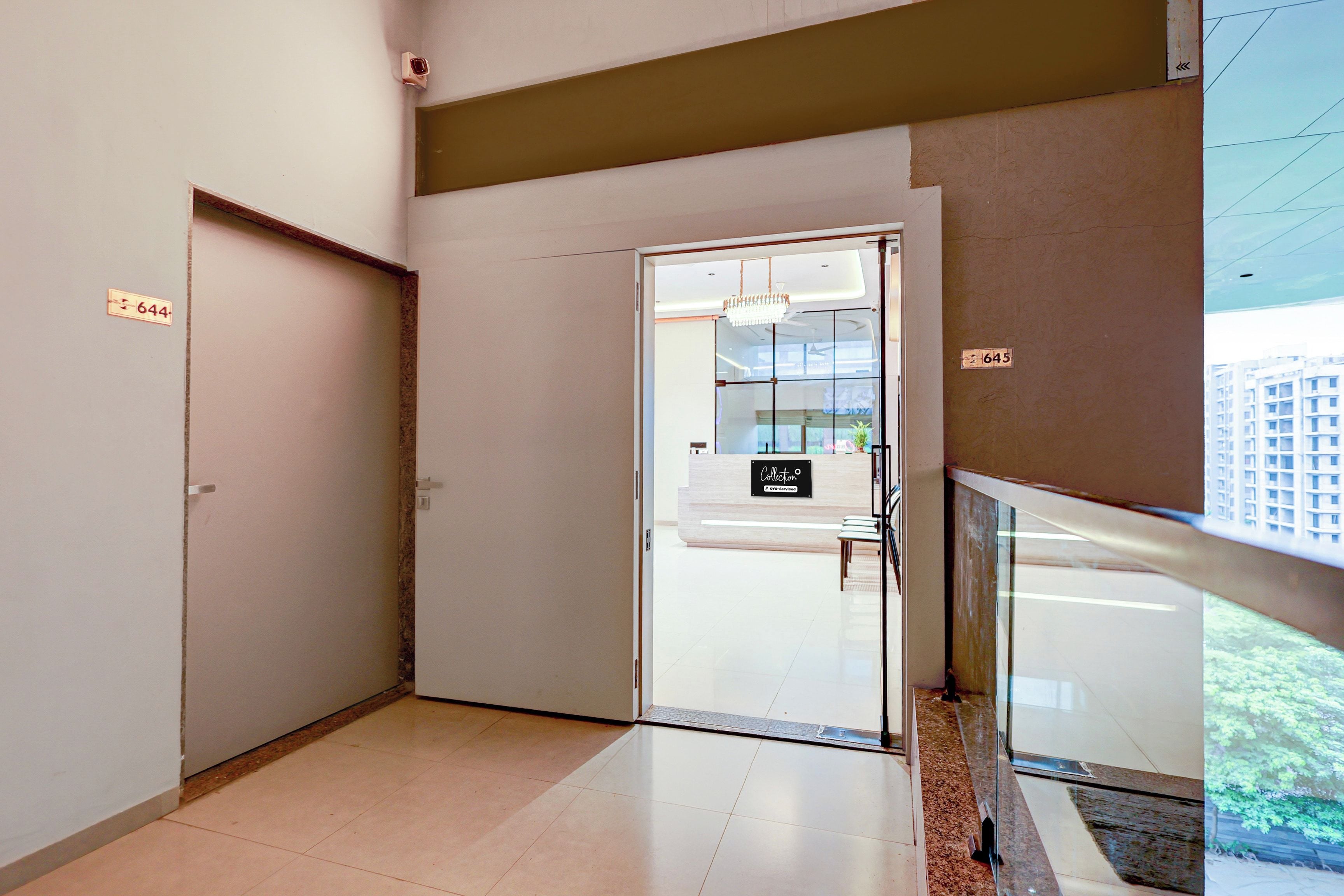 A hotel reception area with a glass door, a reception desk, and a view of the outside.