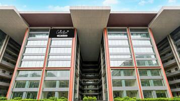 A modern building with a large entrance, multiple floors, and a sign indicating it is a collection of serviced apartments.