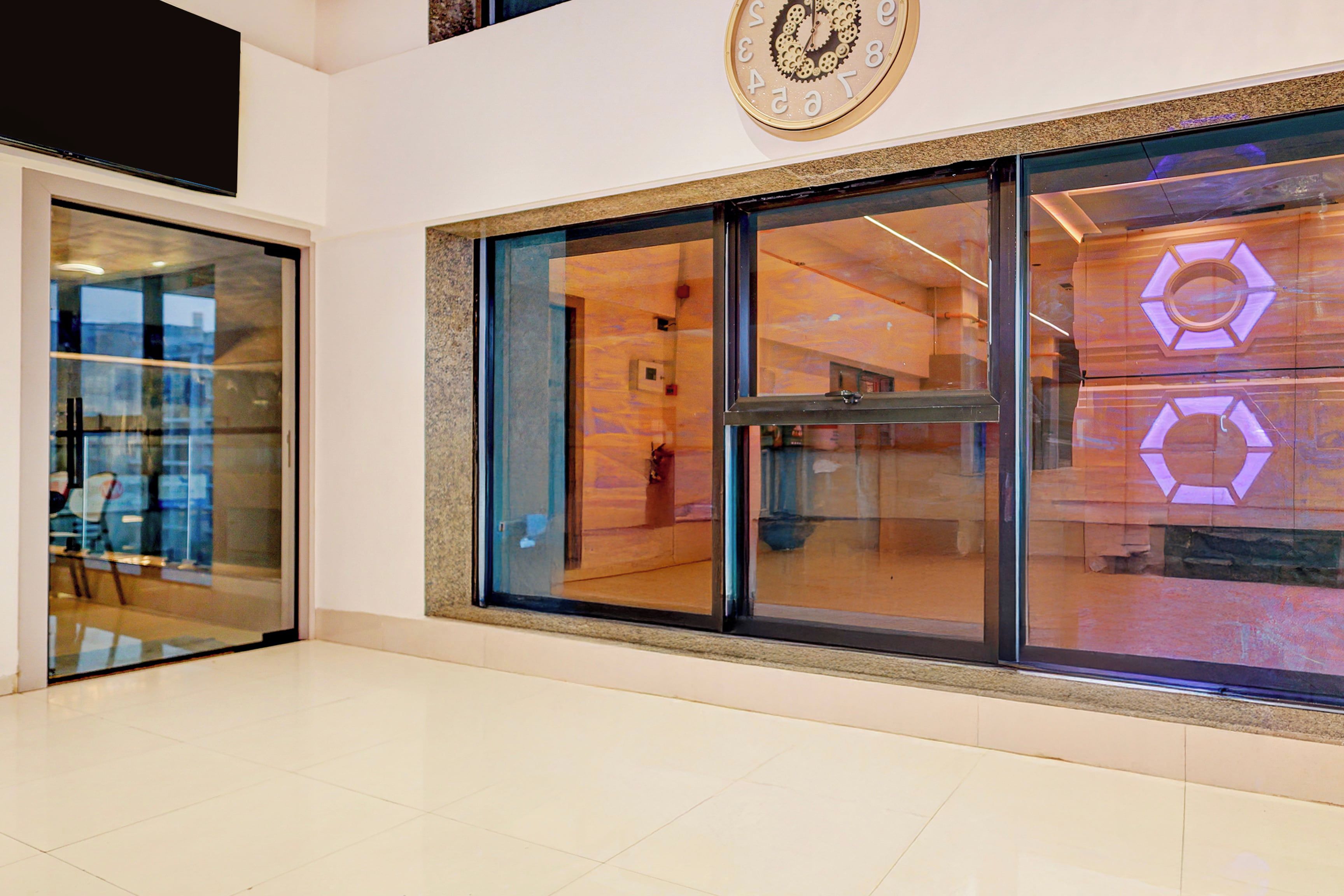 A modern interior with a large glass window, a clock on the wall, and a reflection of a cityscape.