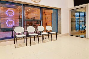 A seating area with four chairs in front of a store window.