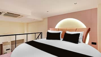 Un dormitorio moderno con una cama grande, un cabecero con luz semicircular y un balcón con barandilla.
