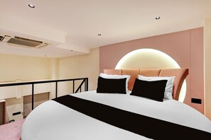 A modern bedroom with a large bed, a headboard with a semi-circular light, and a balcony with a railing.