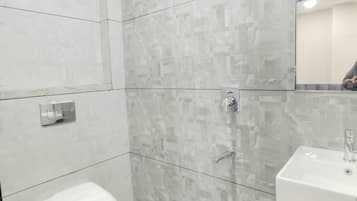 A modern bathroom with a shower, toilet, and sink.