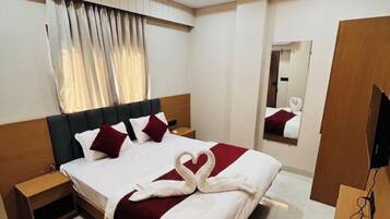 A hotel room with a bed, a nightstand, a mirror, a ceiling fan, and a TV.