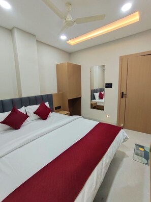 Habitación de hotel con una cama, ventilador de techo, armario y espejo.