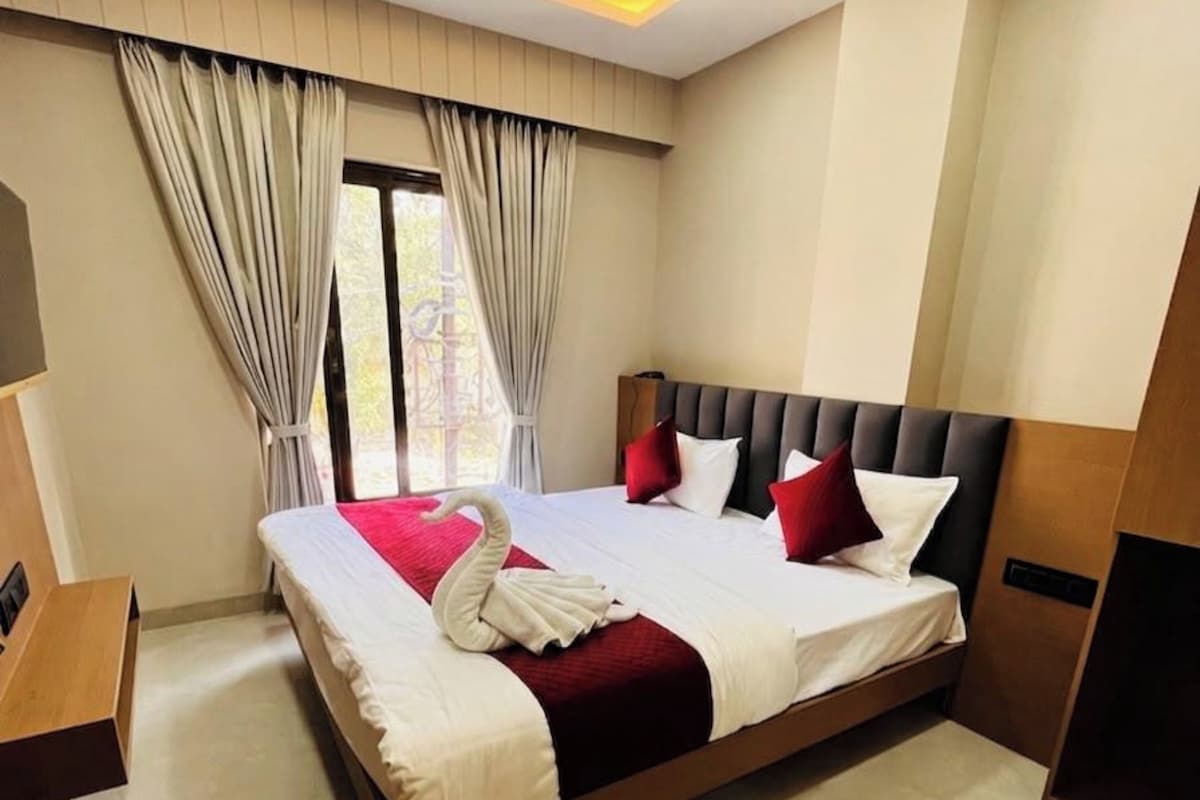 Habitación de hotel con una cama grande, ventilador de techo y vista al exterior.