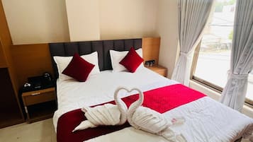 Habitación de hotel con cama, mesita de noche, ventana con cortinas y vista al exterior.