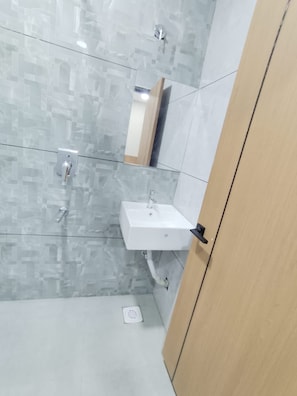 A bathroom with a white sink, a mirror, and a shower area.