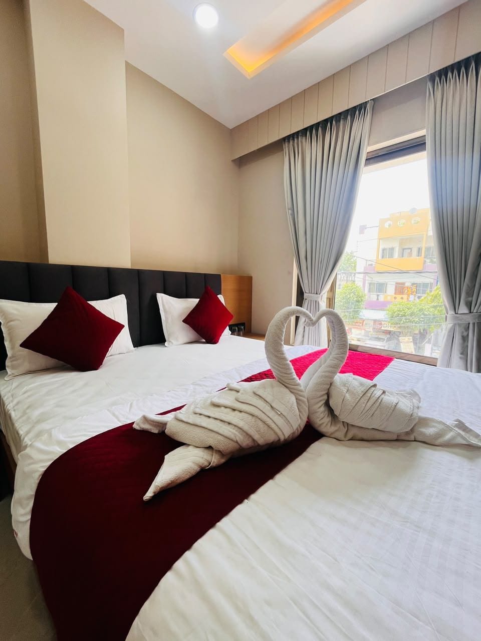 A hotel room with a large bed, a headboard, and a view of the outside.