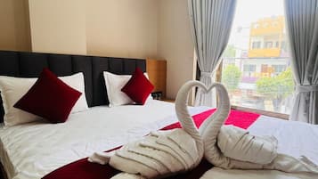 A hotel room with a large bed, a headboard, and a view of the outside.