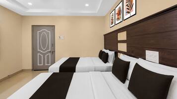 A hotel room with two beds, a wooden headboard, a door with a geometric design, and framed artwork on the wall.