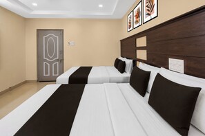 A hotel room with two beds, a wooden headboard, a door with a geometric design, and framed artwork on the wall. - Palette Mahbubabad Railway Station (Mancherial)