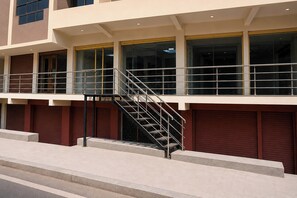 A multi-story building with a central staircase, large windows, and a flat roof.
