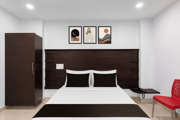 A bedroom with a bed, a wardrobe, a nightstand, a telephone, and a red chair.