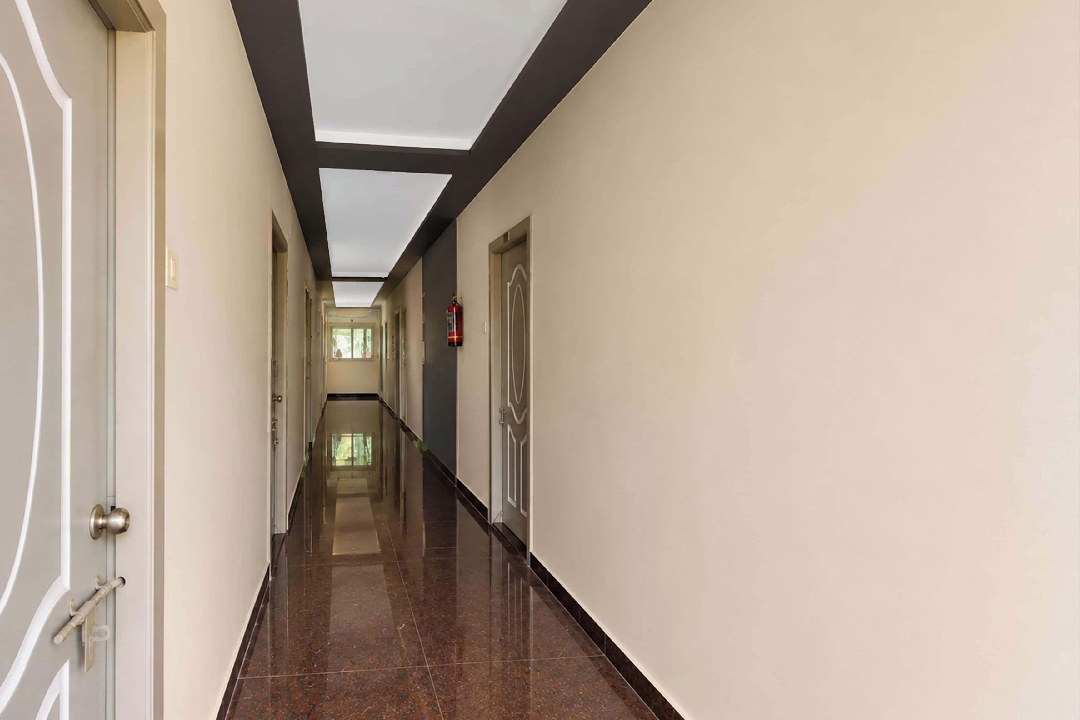 A corridor with a polished floor, a fire extinguisher mounted on the wall, and a door with a modern handle.
