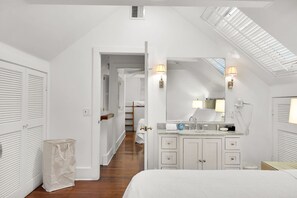 A bedroom with a large bed, a vanity with a mirror, and a skylight. - Jacaranda Cottage 18+ Adult Only cottage near Duval St (Key West)