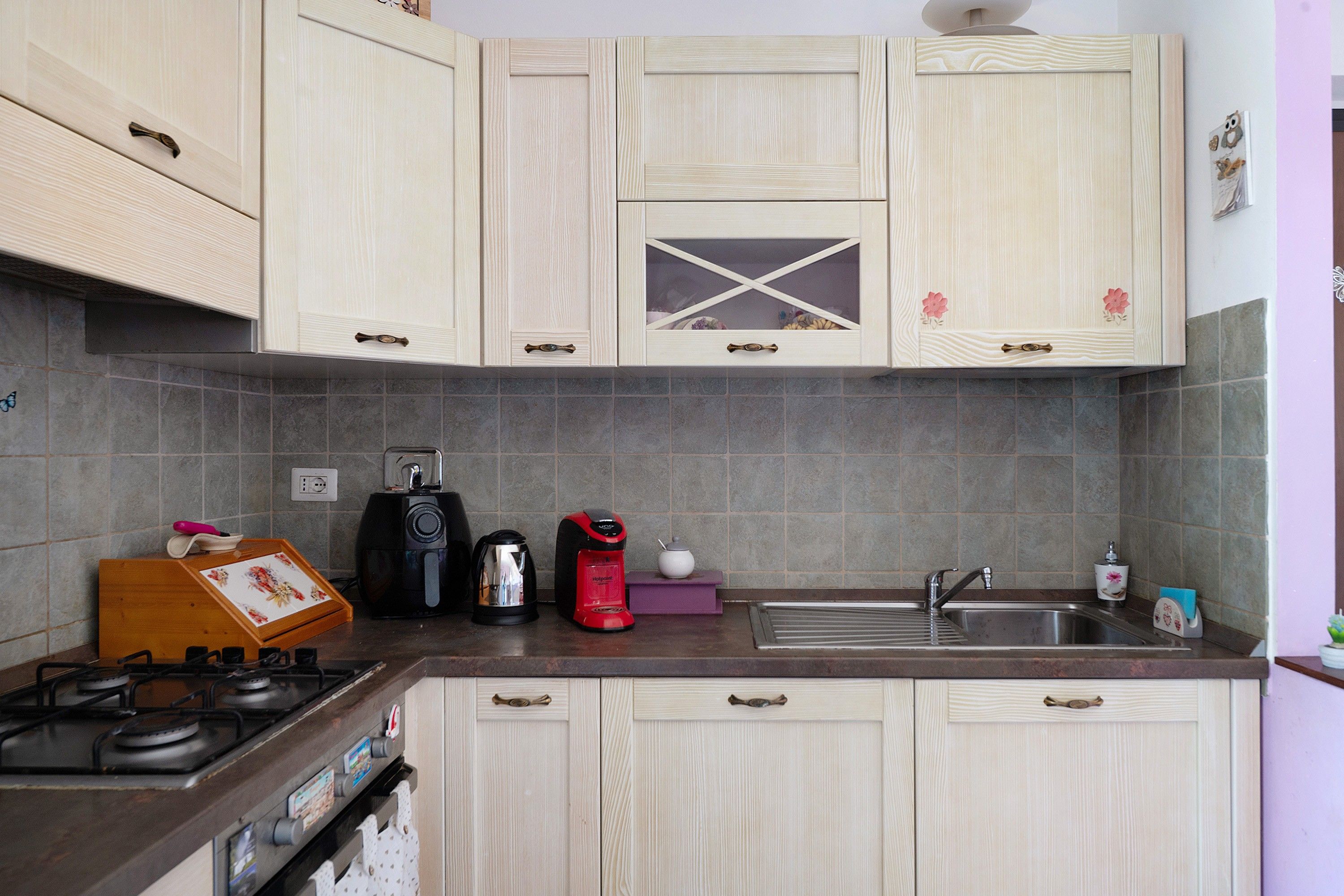 A kitchen with light-colored cabinets, a gas stove, a coffee maker, and a kettle.