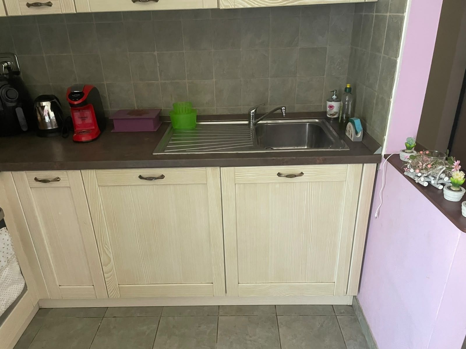 A kitchen with a sink, a coffee maker, and a green cup holder.