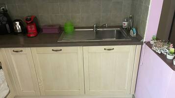 A kitchen with a sink, a coffee maker, and a green cup holder.