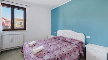 Una camera da letto con un letto, una finestra, un termosifone e un comò.