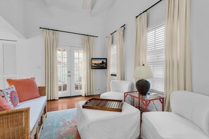 A hotel room with a bed, a chair, a small table, and a television. - Frangipani Cottage  18+ Adult Only cottage near Duval St (Key West)