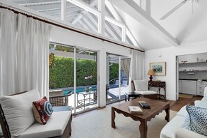 A spacious living room with a large sliding glass door leading to a pool area, a dining table, and a kitchen area. - Magnolia Manor 18+ Adult Only retreat near Duval Street (Key West)