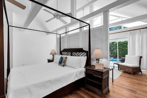 A four-poster bed with a ceiling fan, white bedding, and a view of a pool through a large window. - Magnolia Manor 18+ Adult Only retreat near Duval Street (Key West)
