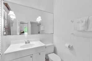 Ein Badezimmer mit einem weißen Waschbecken, einem Spiegel und einer Toilette.