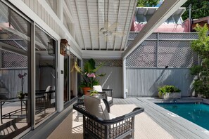 Eine Außenpatio mit Pool, Sitzbereich und einem überdachten Bereich mit Deckenventilator.