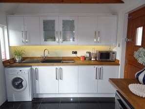 A compact kitchen with a washing machine, a microwave, and a sink.