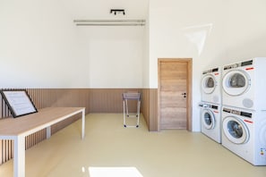 Ein Waschraum mit einer Holztür, einem Metalltrockner und einer an der Wand befestigten Waschmaschine.