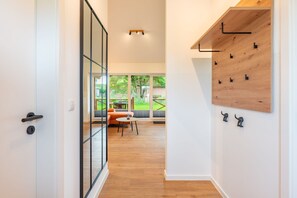 Ein modernes Interieur mit Holzboden, Glastür und einer Sitzecke mit Tisch und Stühlen.