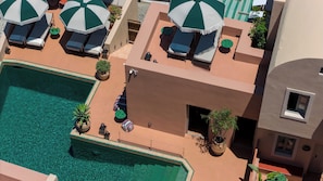 A rooftop pool area with lounge chairs and umbrellas, a small seating area, and potted plants. - Terra Verde Oia Suites - Patio Grand Suite with Inner Courtyard View (Oia)