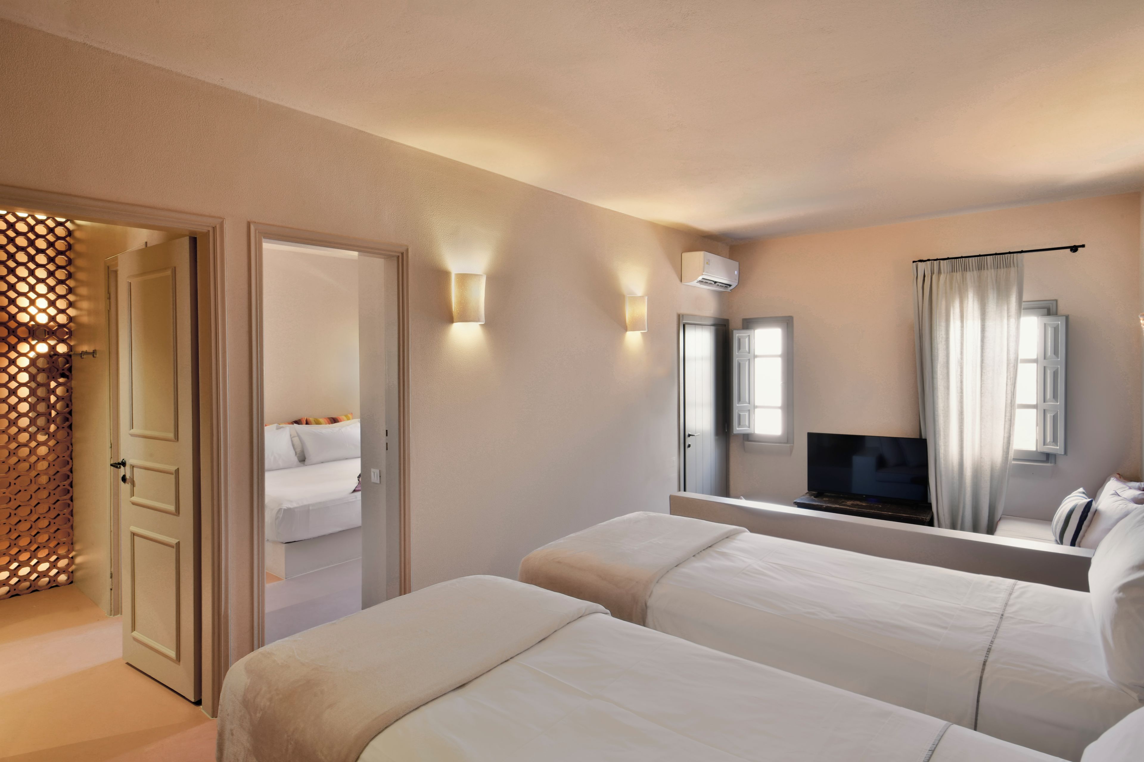 Une chambre d’hôtel avec deux lits, une télévision et un miroir qui reflète la pièce.