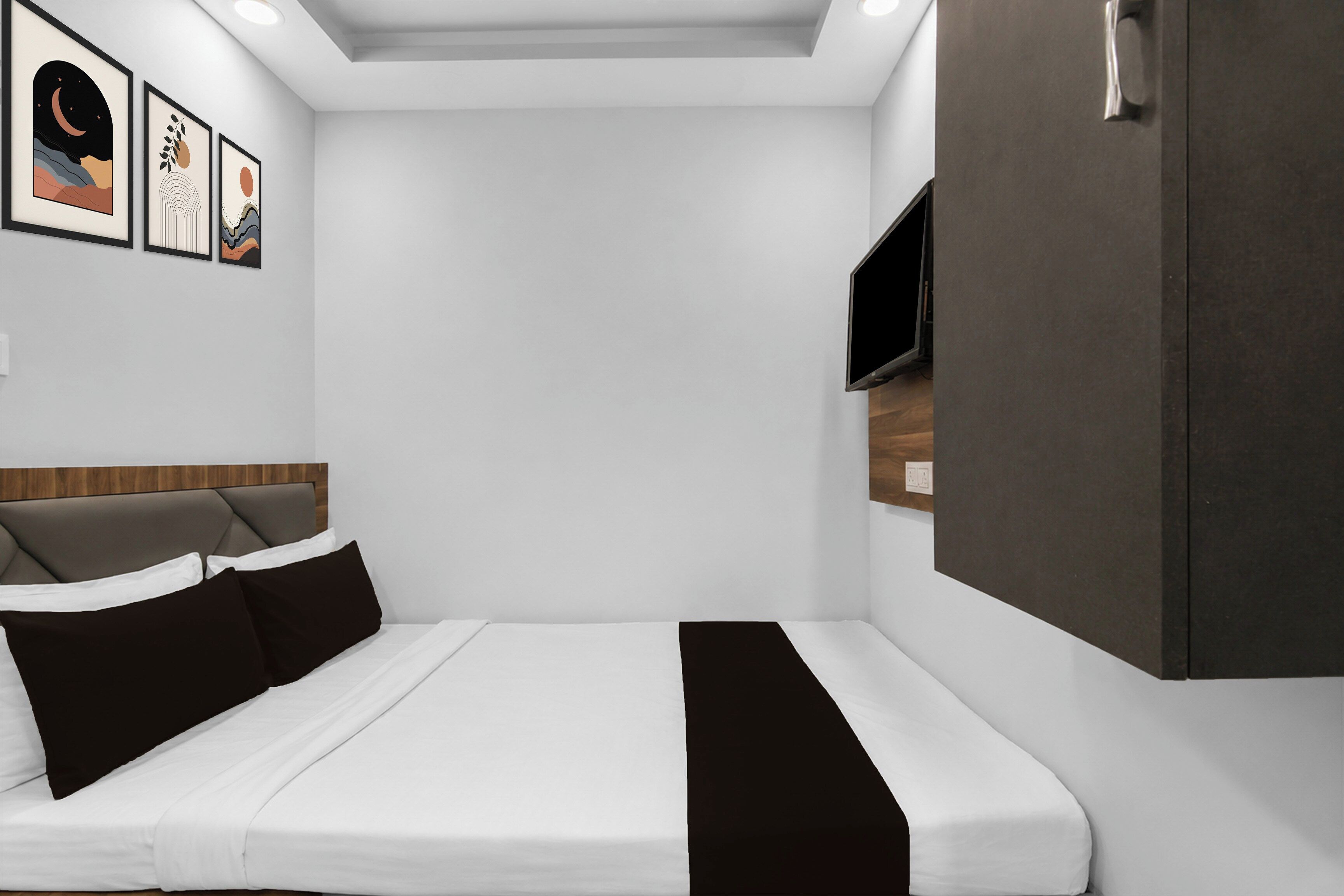 Un dormitorio moderno con cama, armario, televisor de pantalla plana y cuadros en la pared.