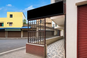A building with a gated entrance, a tiled pavement, and a street in the background. - Hotel O Ripon Street Kolkata (Kolkata)
