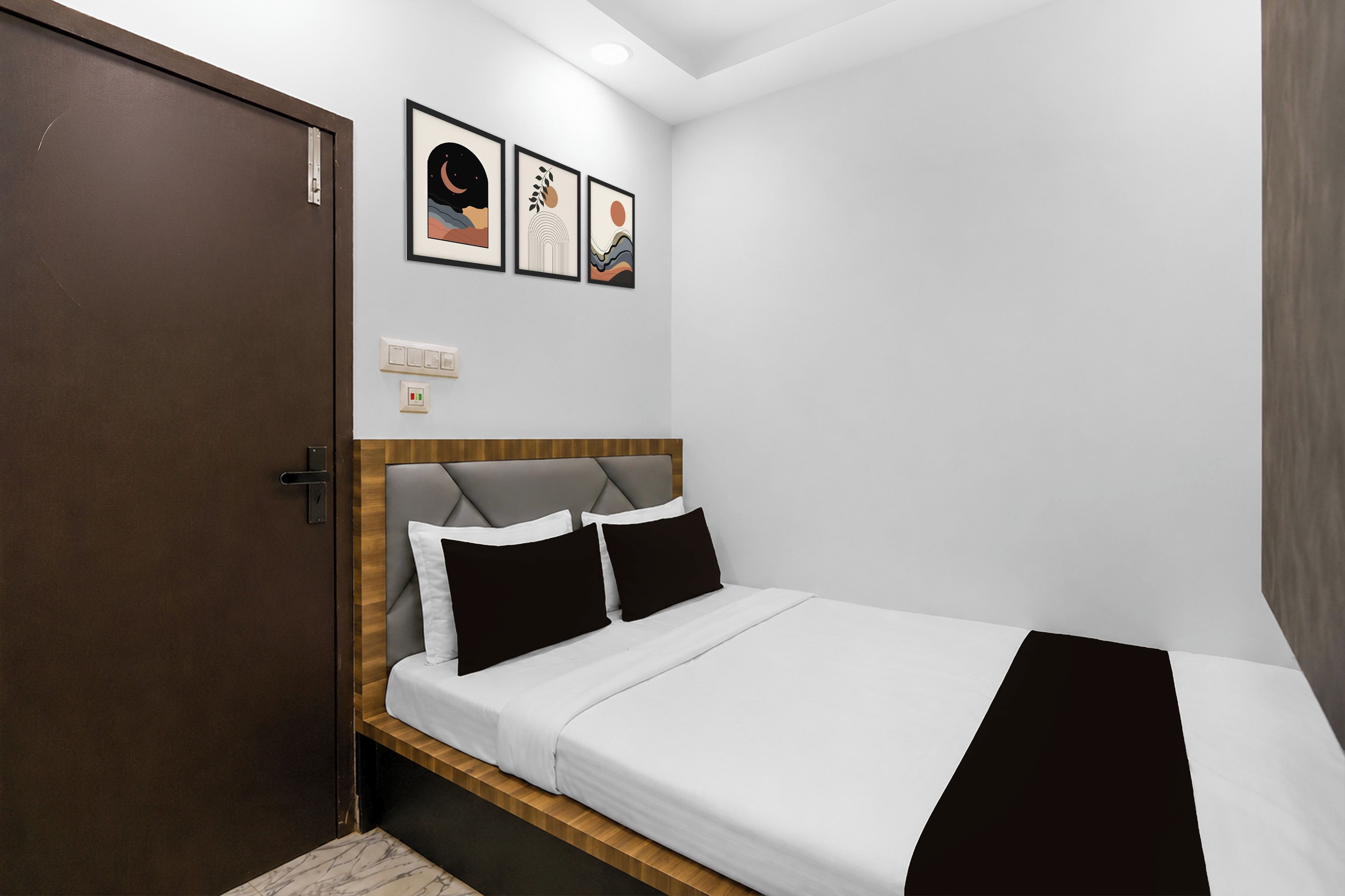 Un dormitorio con cama, cabecera de madera, una puerta y tres cuadros en la pared.