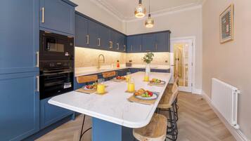 Una cocina moderna con armarios azules, una encimera blanca y una zona de desayuno con fruta y jugo.