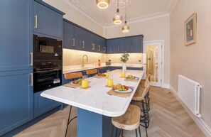 Una cocina moderna con armarios azules, una encimera blanca y una zona de desayuno con fruta y jugo.