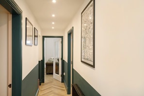 A hallway with a wooden floor, a door leading to a room, and framed artwork on the walls. - Ousegate Skyline Retreat, sleeps 6 (York)