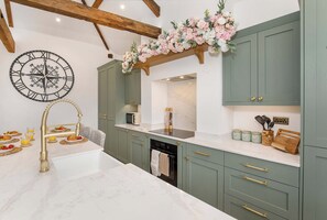 A kitchen with a central island, a clock, and a decorative floral arrangement. - Ousegate Skyline Retreat, sleeps 6 (York)