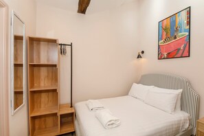 A bedroom with a bed, a wooden wardrobe, a painting, and a nightstand. - Ousegate Skyline Retreat, sleeps 6 (York)