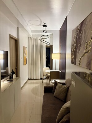 Ein modernes Hotelzimmer mit einer Couch, einem Essbereich und einem Fernseher.