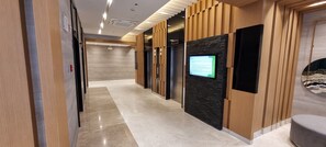 A modern hallway with a digital display, wooden paneling, and a marble floor. - Modern Hotel-Style Condo Near MOA Arena & Mall of Asia and Dedicated Parking (Pasay City)
