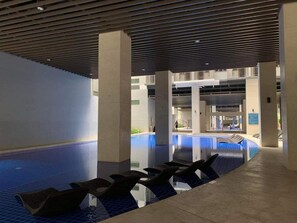 Ein Innenpool mit klarem Wasser, umgeben von einem gefliesten Boden und einer Decke mit Rillendesign.