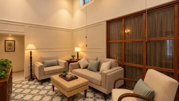 A living room with a sofa set, a coffee table, and a large window with curtains.