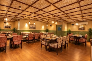 Un restaurante con suelo de madera, sillas estampadas y mesas dispuestas para comer.